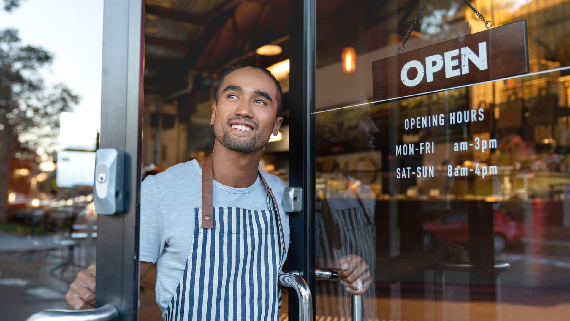 A business owner opens the door of his shop